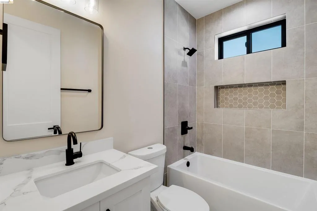 Bathroom featuring a white vanity with a marble-finish countertop, undermount sink, and matte black fixtures