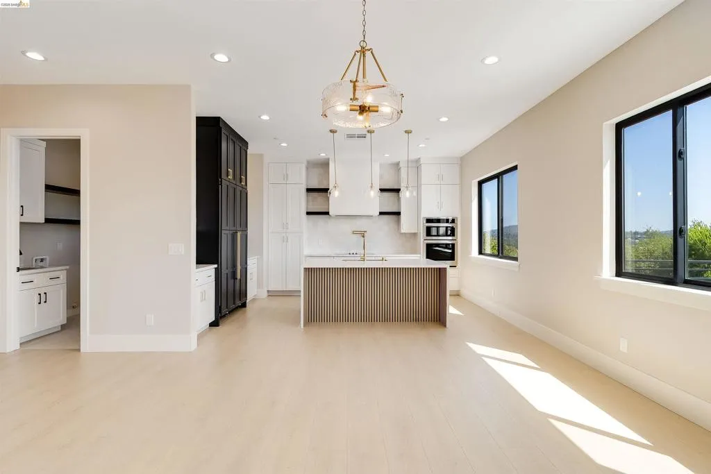 Open-concept living space featuring light wood-finish flooring, recessed lighting, and a modern kitchen