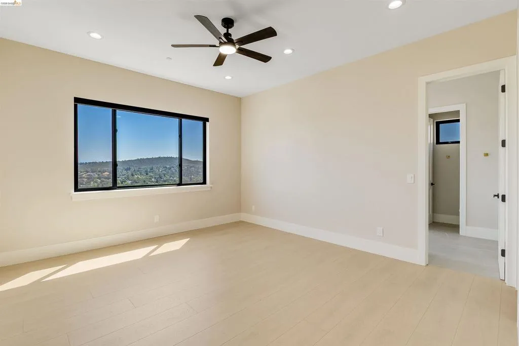 Spacious room featuring light wood-finish flooring, recessed lighting, and a modern ceiling fan