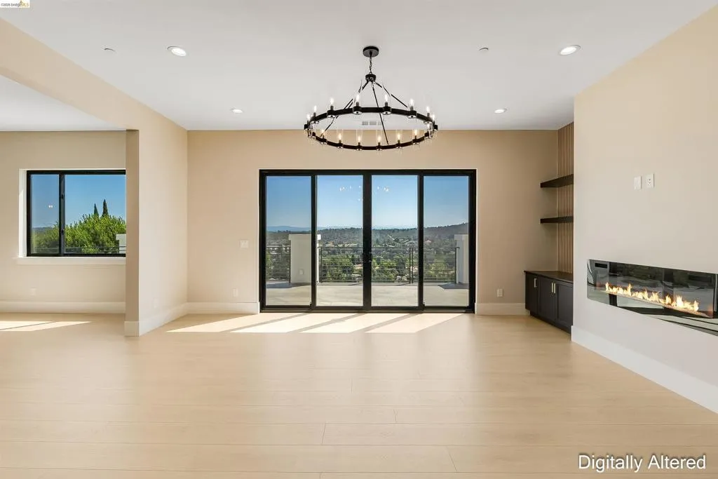 Spacious room featuring light wood-finish flooring, a contemporary linear fireplace, and a large multi-panel sliding glass door