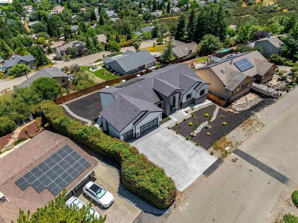 Contemporary residence featuring a dark gray roof, a two-car garage with frosted glass panels, and a concrete driveway