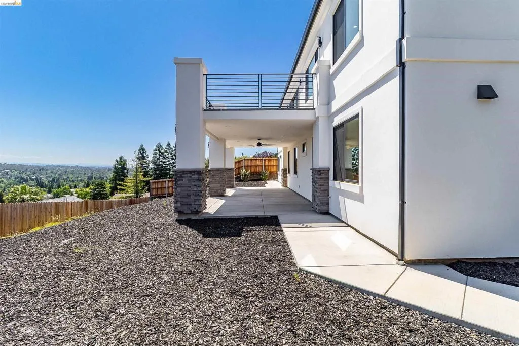 Modern exterior featuring a second-story balcony with metal railing, a covered patio, and a contemporary ceiling fan