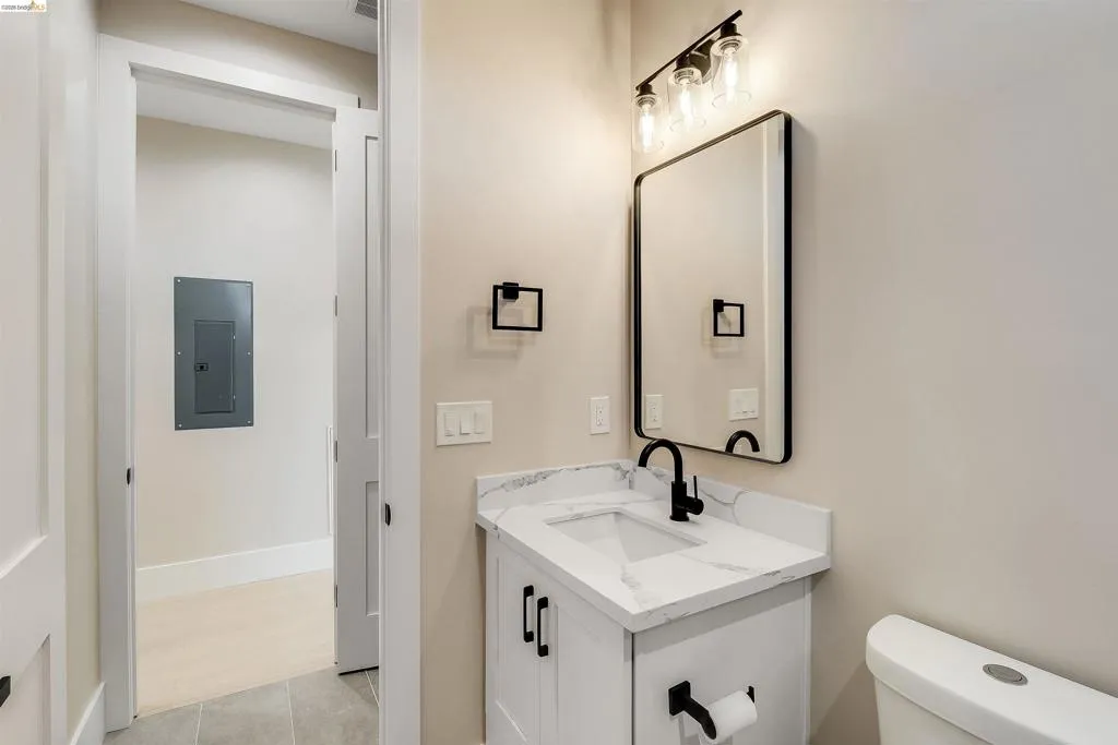 Bathroom featuring a white vanity with a marble-look countertop and integrated sink, a matte black faucet, and a rectangular mirror with a black frame