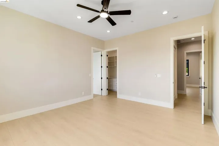 Spacious room featuring light wood-finish flooring, recessed lighting, a ceiling fan, and access to a built-in closet system