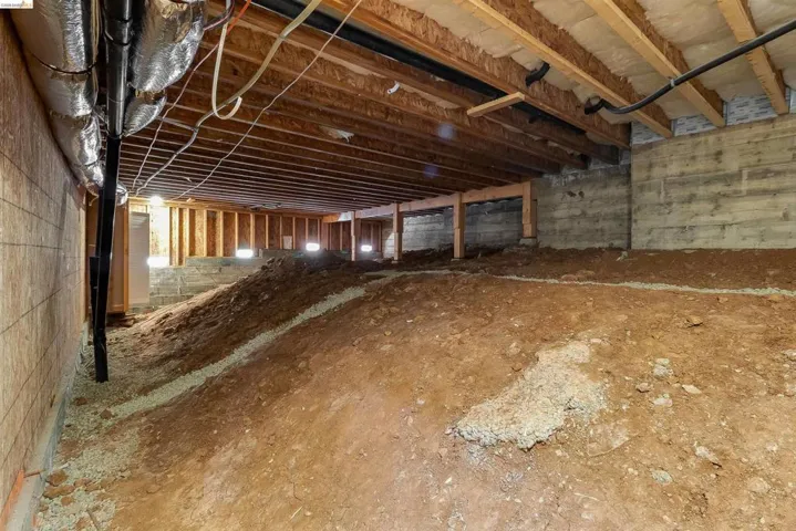 Unfinished crawl space with exposed wood joists and subflooring