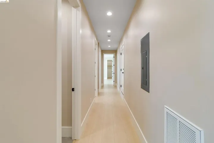 Long hallway featuring light wood-finish flooring, recessed lighting, and neutral wall tones