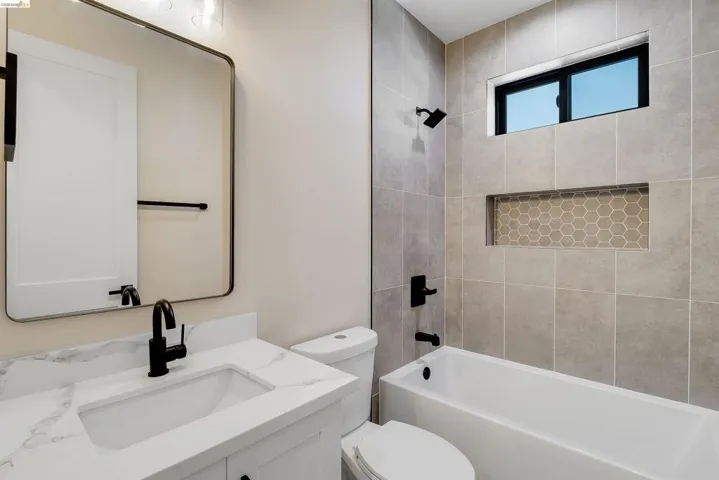 Bathroom featuring a white vanity with a marble-finish countertop, undermount sink, and matte black fixtures