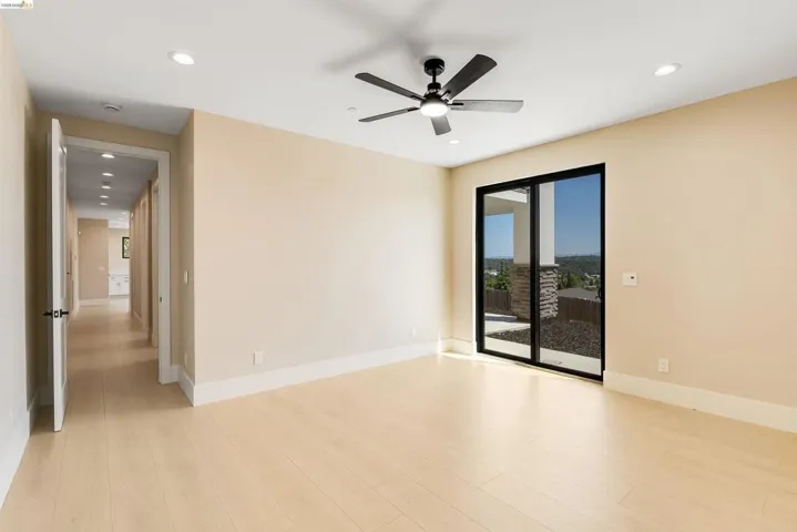 Spacious room featuring light wood-finish flooring, recessed lighting, and a modern ceiling fan