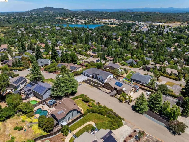 Aerial view showcasing a residential neighborhood with varied architectural styles, mature trees, and individual properties featuring solar panels