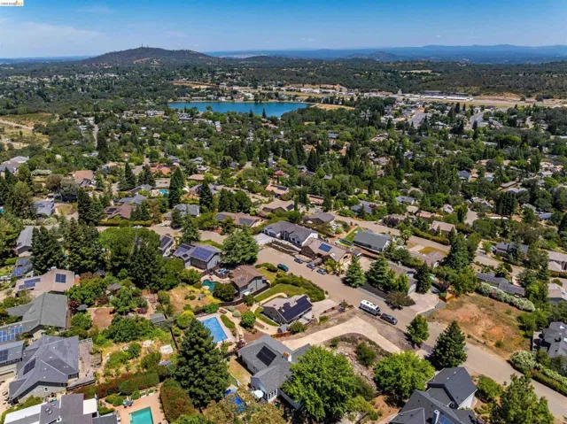 Expansive aerial capturing a residential area with a prominent body of water and distant mountains