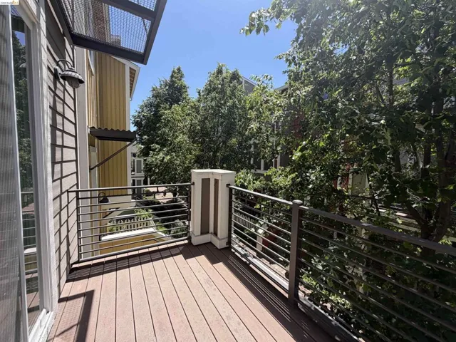 Balcony featuring composite decking, horizontal metal railings, and an exterior wall light fixture