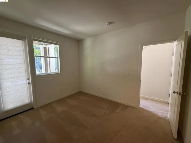 Interior room featuring light-toned carpeting, a white paneled door, and a single window with a shade