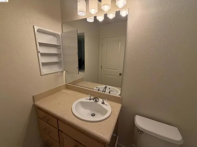 Bathroom vanity featuring a light-toned countertop, undermount sink, and chrome faucet
