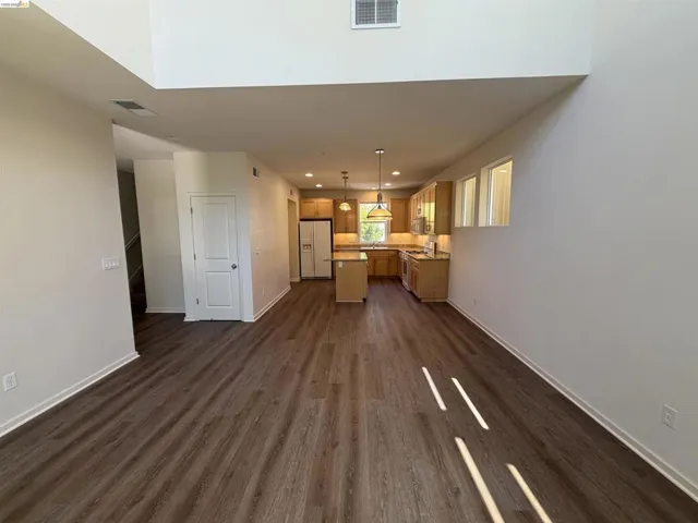 Open-concept living area featuring wood-finish flooring, high ceilings, and a contemporary kitchen