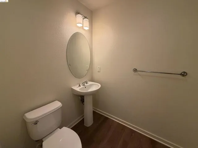 Pedestal sink with chrome fixtures, oval mirror, and a two-light vanity fixture