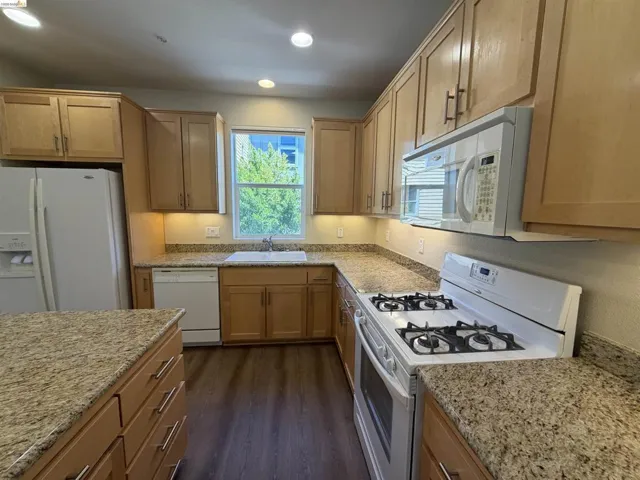 Kitchen featuring wood-finish cabinetry, light-toned countertops, a white gas range, and a built-in microwave