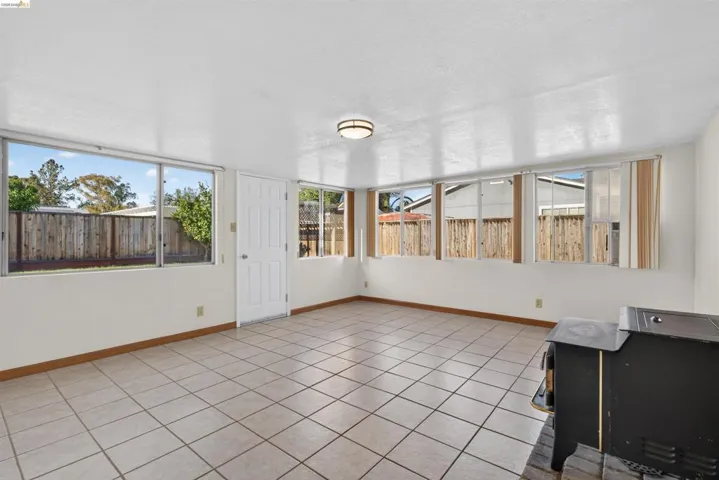 Spacious room featuring light-colored square tile flooring, multiple windows providing natural illumination, and a ceiling-mounted light fixture