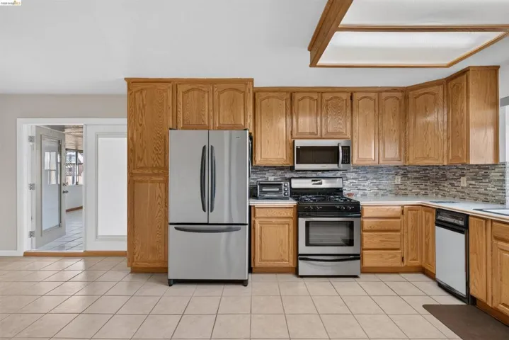 Kitchen featuring light wood cabinetry, stainless steel appliances, and a mosaic tile backsplash