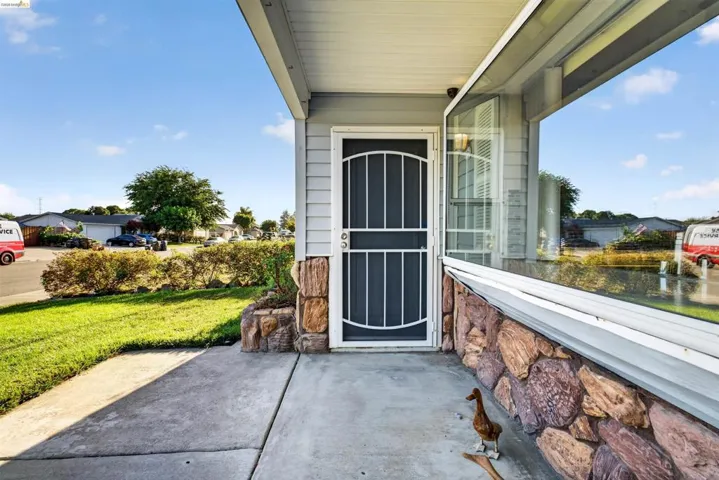 Front entrance featuring a security screen door, stone facade detailing, and a large picture window