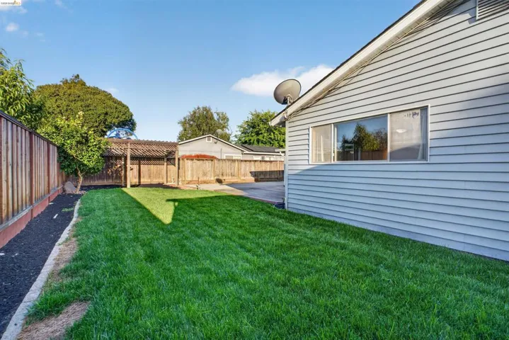 Spacious backyard featuring a lush lawn, privacy fencing, and a built-in pergola