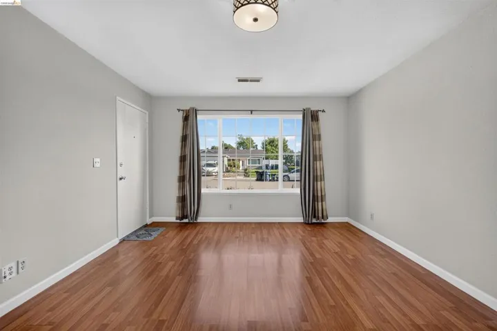 Spacious interior with rich wood-finish flooring, light gray wall tones, and white baseboards