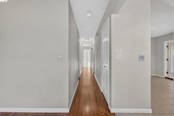Hallway featuring wood-finish flooring and light gray walls