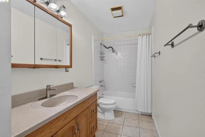 Bathroom featuring a wood-finish vanity with an integrated sink and light-toned countertop