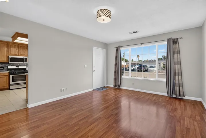 Living area featuring wood-finish flooring, a large multi-pane window, and a drum ceiling light fixture