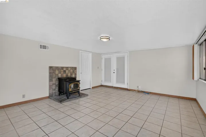 Spacious interior with tile flooring, featuring a wood-burning stove with a stacked stone surround