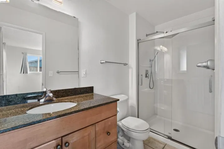 Bathroom featuring a wood-finish vanity with a stone-finish countertop, undermount sink, and chrome faucet