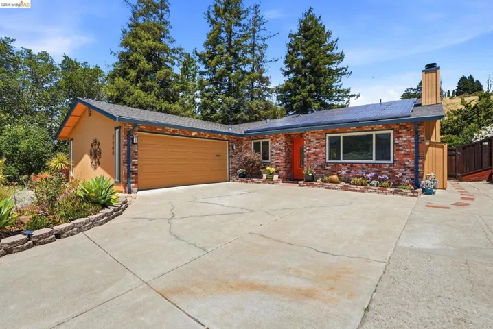Brick and stucco facade home with an attached garage, solar panels, and a concrete driveway