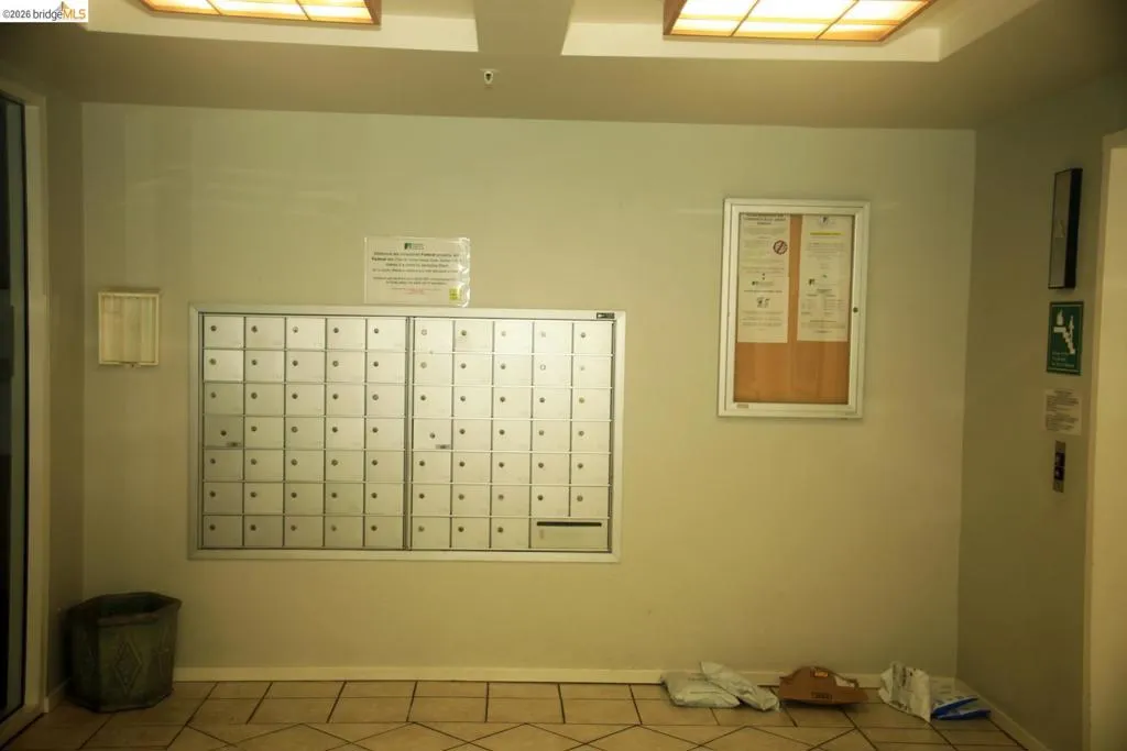 Secured wall-mounted mailboxes with a central bulletin board and overhead ceiling lighting
