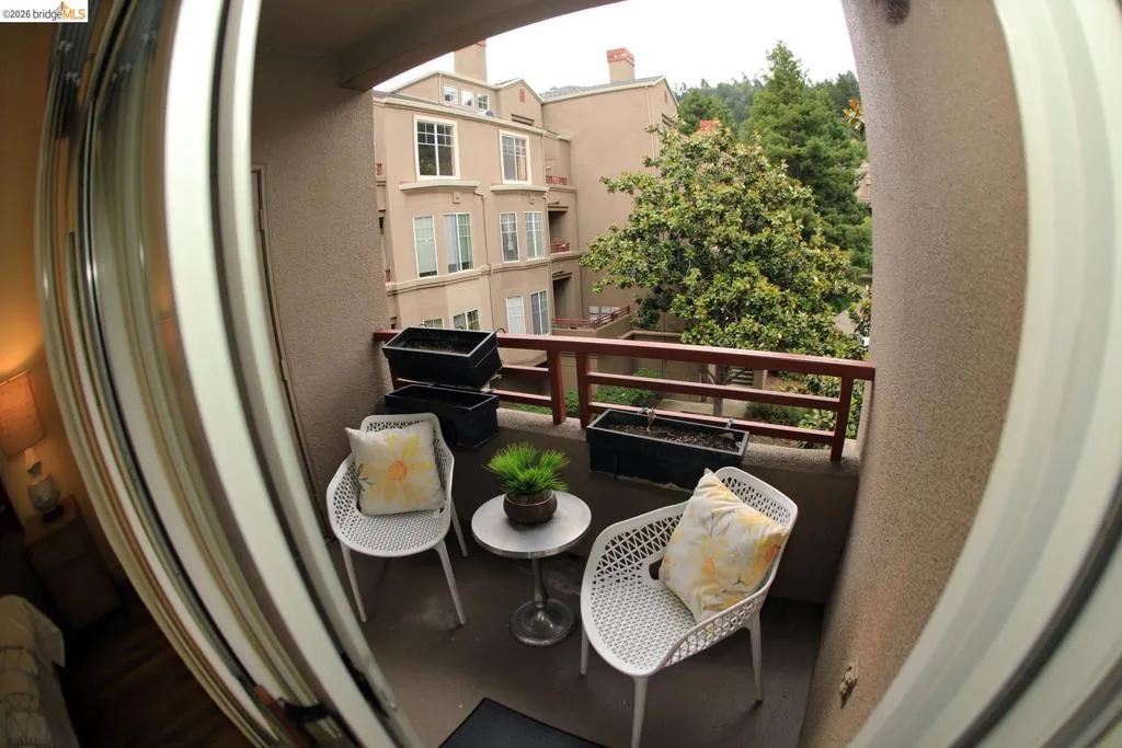 Private balcony with a textured exterior wall, concrete flooring, and a wooden railing