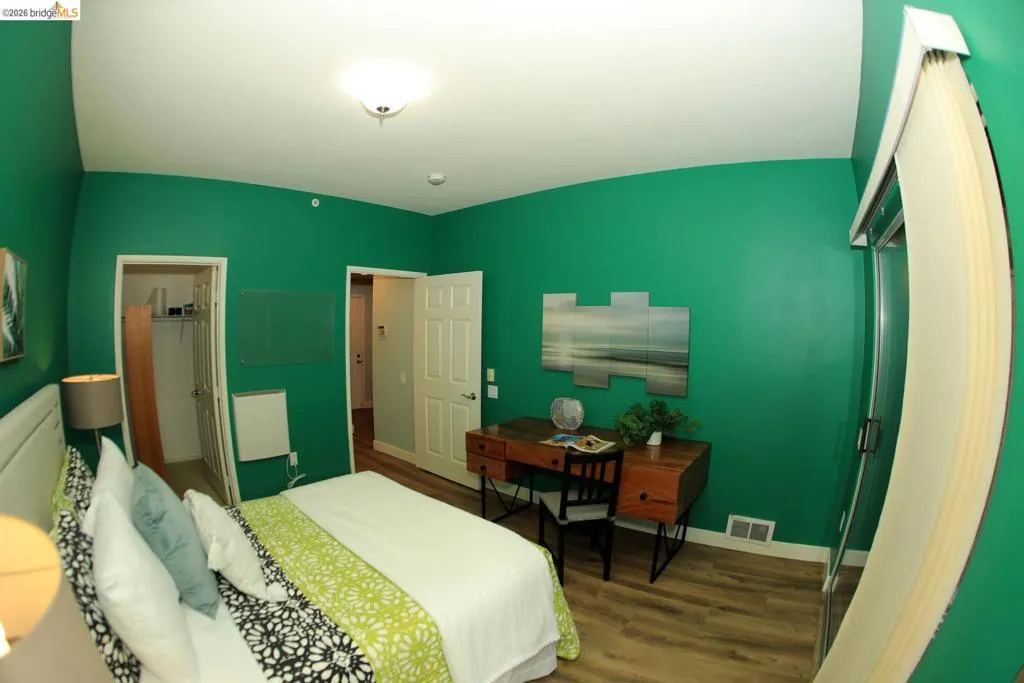 Bedroom featuring wood-finish flooring, a ceiling-mounted light fixture, and a built-in closet with shelving