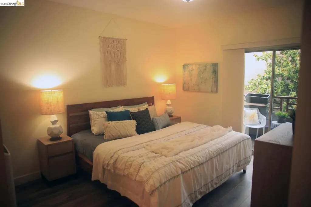 Spacious bedroom featuring wood-finish flooring and a sliding glass door opening to an outdoor balcony