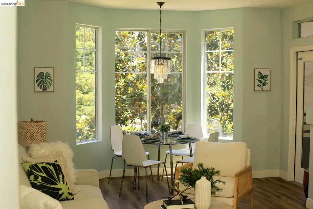 Bay window dining area featuring a contemporary chandelier and wood-finish flooring