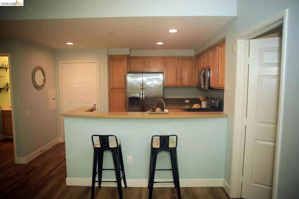 Kitchen featuring stainless steel appliances, wood cabinetry, recessed lighting, and a breakfast bar