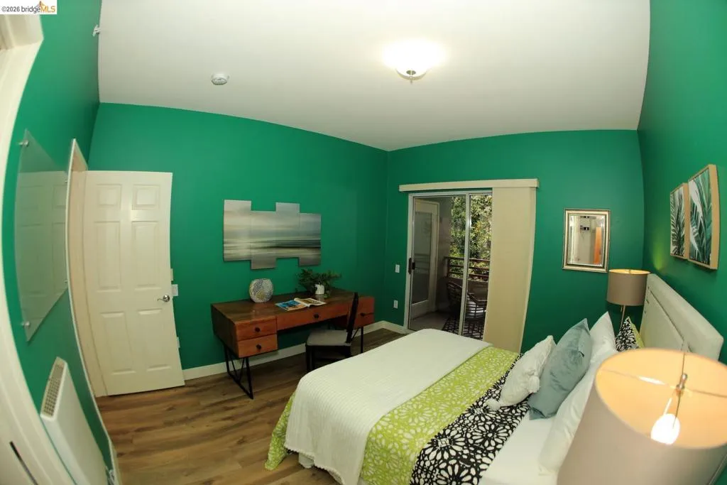Room featuring wood-finish flooring, a white paneled door, and a sliding glass door leading to an outdoor balcony