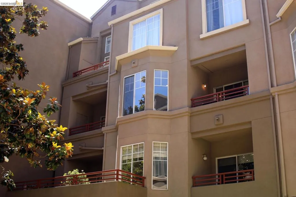 Multi-story building facade featuring stucco siding and multiple private balconies with red railings