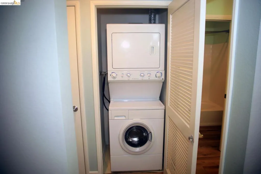 Stackable washer and dryer unit within a dedicated closet space, featuring louvered bifold doors