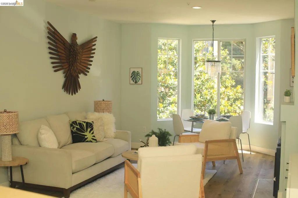 Spacious living area featuring light-toned walls and wood-finish flooring