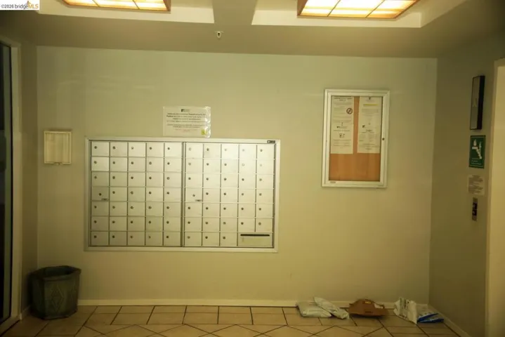 Secured wall-mounted mailboxes with a central bulletin board and overhead ceiling lighting