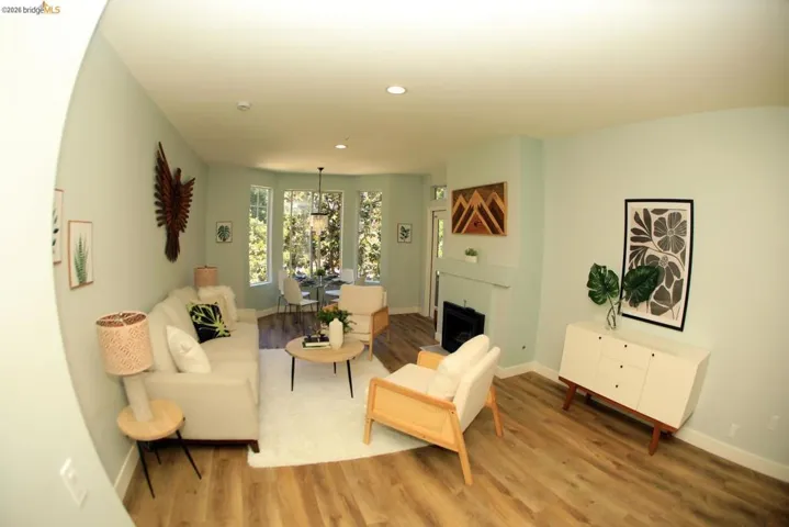 Open-concept living space featuring wood-finish flooring, recessed lighting, and a fireplace with a mantel