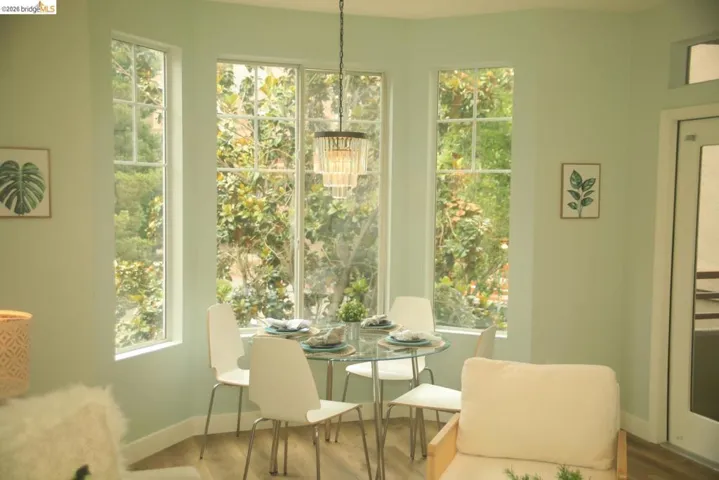 Bay window dining area with multiple picture windows, a decorative chandelier, and wood-finish flooring