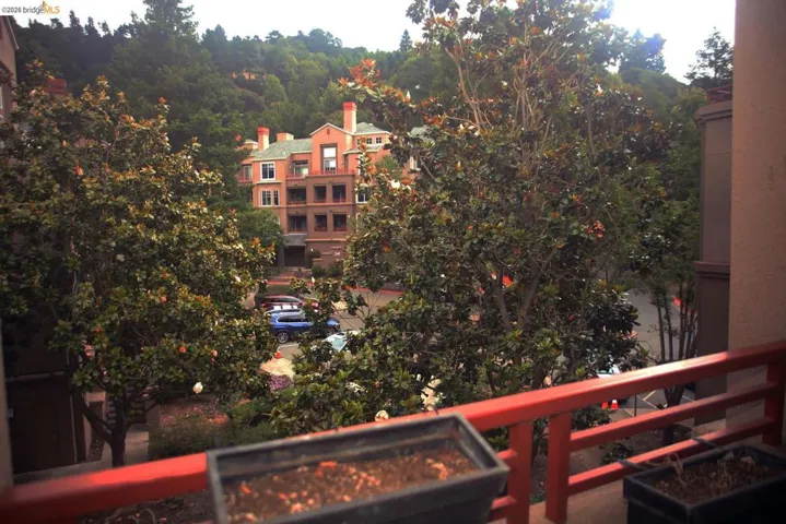 Balcony with a red railing and planter boxes, offering a verdant outlook
