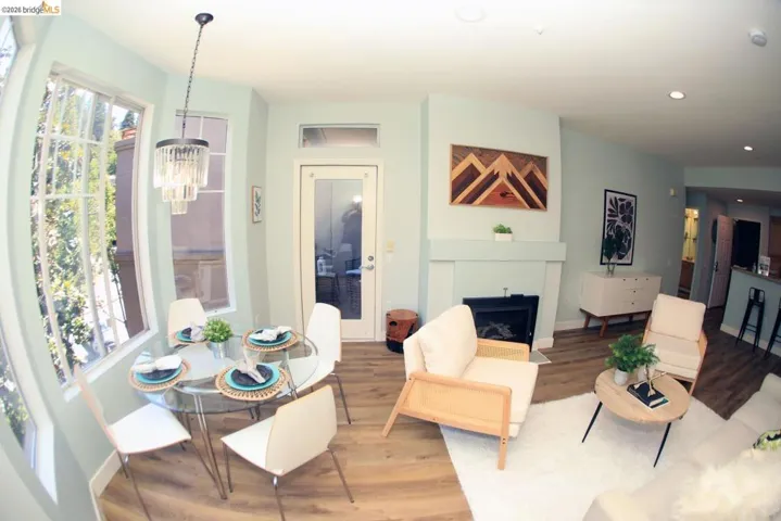 Open-concept living area featuring wood-finish flooring, a contemporary fireplace, and a dining area with a modern chandelier