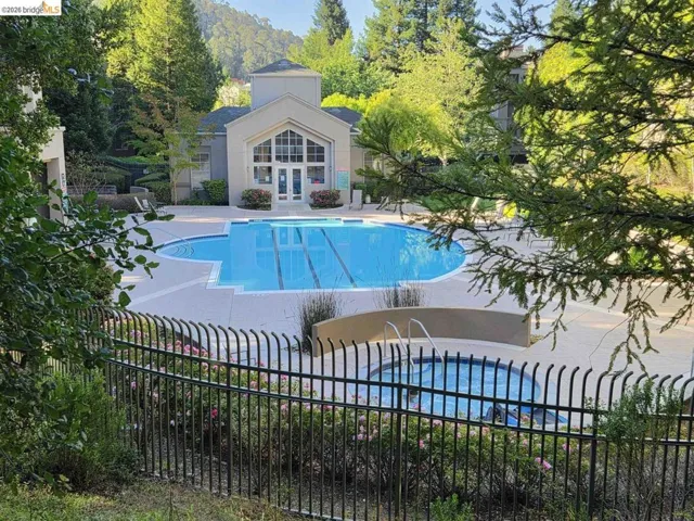 Community swimming pool featuring a large main pool with lane markers, a separate spa, and surrounding concrete decking