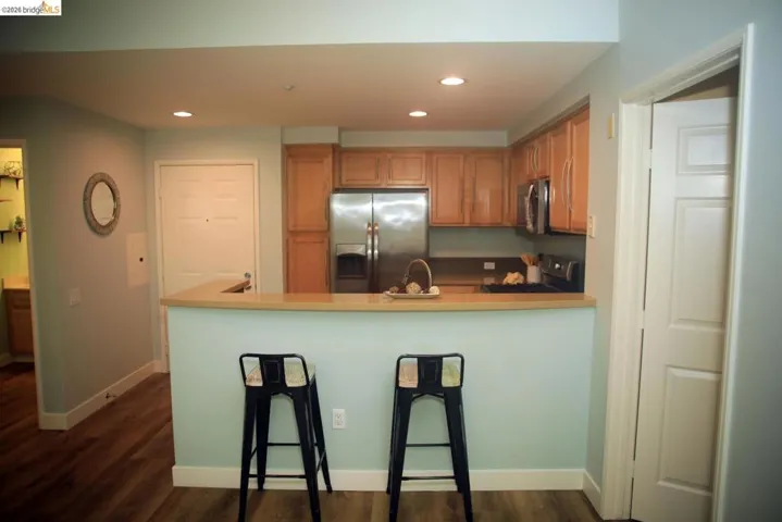 Kitchen featuring stainless steel appliances, wood cabinetry, recessed lighting, and a breakfast bar