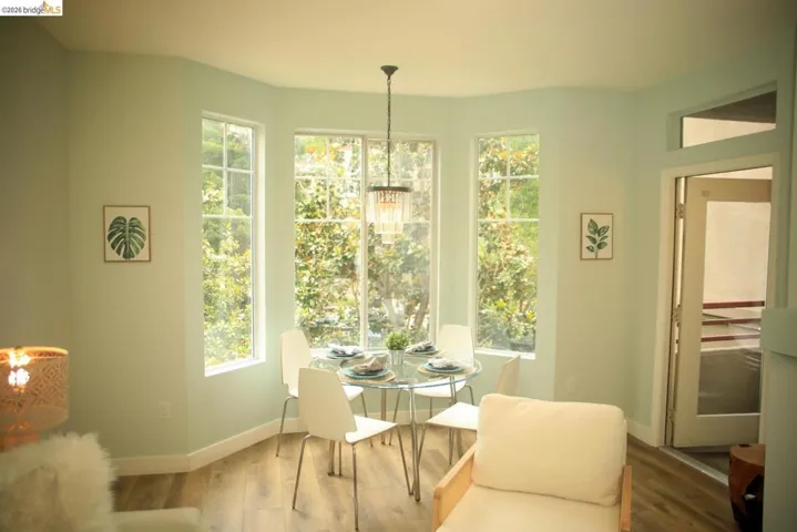 Bay window dining area featuring multiple windows, wood-finish flooring, and a chandelier-style light fixture