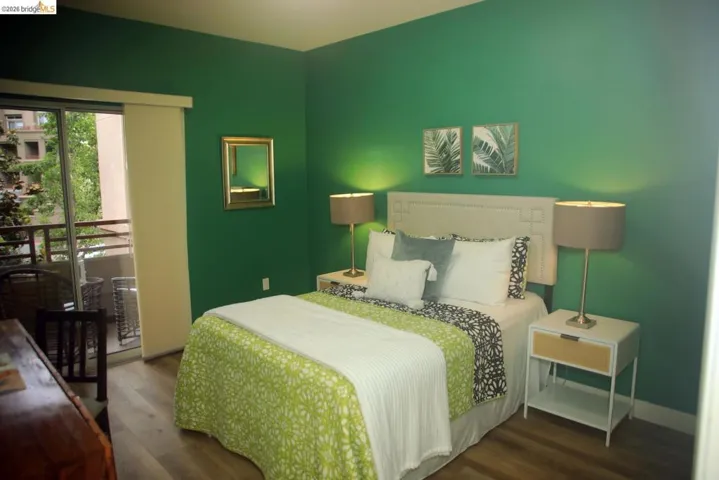 Bedroom featuring wood-finish flooring and a sliding glass door opening to an outdoor balcony with a metal railing